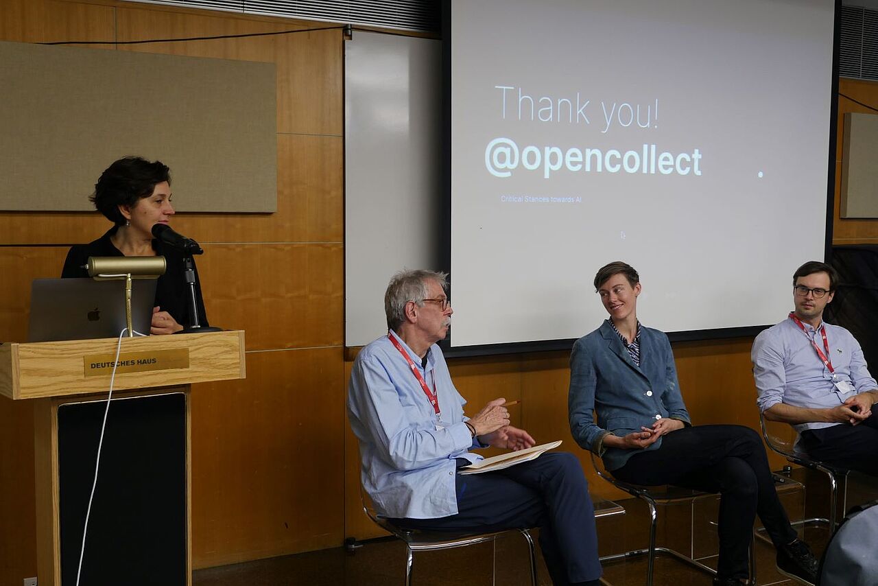 Speakers of the panel: Social and Environmental Perspectives on AI. Gergana Vladova stand behind the podium. Dave Rejeski sits on the left, next to Caroline Woolard. To the rights sits André Ullrich. Behind them the slide reads: Thank You @opencollect.