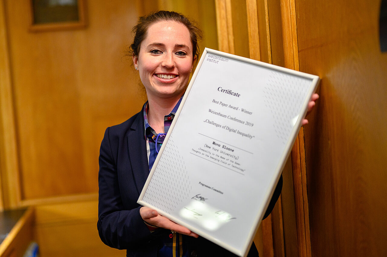 Dr. Mona Sloan hält freudestrahlend die Urkunde des Best Paper Awards in die Kamera