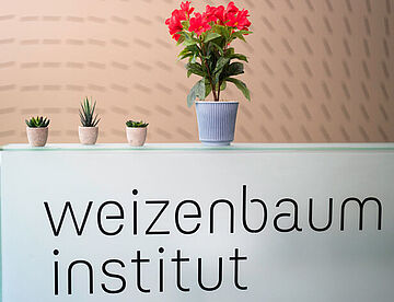 Das Bild zeigt einen Tresen mit der Aufschrift Weizenbaum-Institut. 