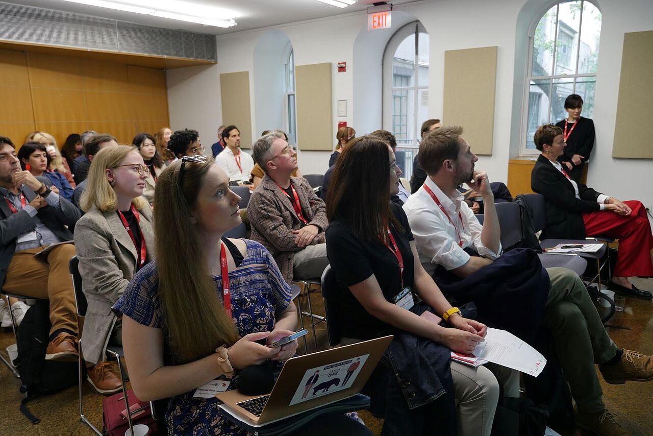 The audience photographed from the first row. A small room with around 40 people sitting on chairs. 